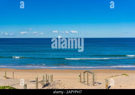 Strandeingang mit Holzgeländer und ruhigem Meerblick Stockfoto