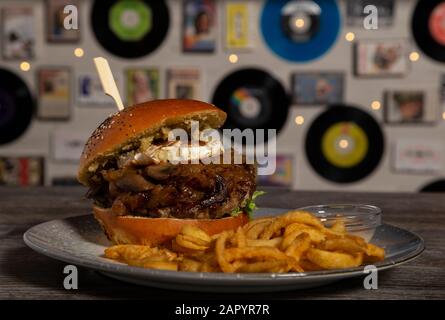 Hausgemachter Rinderburger mit Ziegenkäse, karamellisierter Zwiebel und pommes frites. Isoliertes Bild Stockfoto