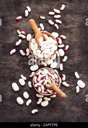 Farbige Bohnen in Holzbechern auf dunklem Woodenhintergrund. Stockfoto