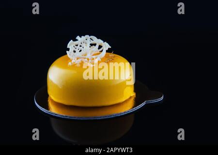 Mousse Kuchen mit Mango-Püree, Sahne und frischen Früchten auf schwarzem Hintergrund. Stockfoto