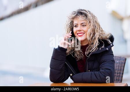 Schöne cacuasianische Frau mit Smartphone. Girl Blonde lockiges Haar mit Platz für Text Stockfoto