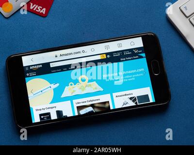 In dieser Abbildung ist eine Online-Shopping-Website von Amazon auf einem Android-Mobilgerät auf blauem Hintergrund mit Kreditkarten und Tastatur zu sehen Stockfoto