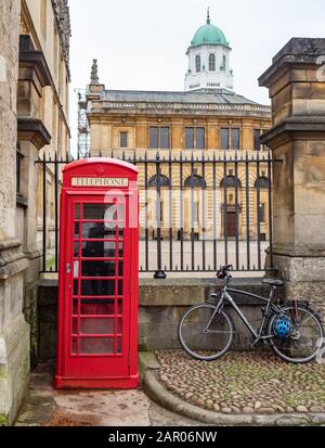 Traditioneller roter Telefonkasten in der Catte Street, Oxford mit dem Sheldonian Theatre Stockfoto