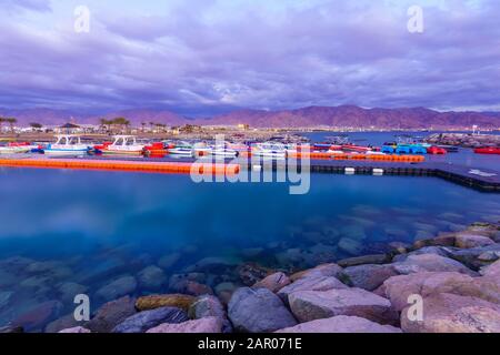 Eilat, Israel - 17. Januar 2020: Abendszene des neuen Jachthafens und der neuen Hotels, mit Einheimischen und Besuchern und Aqaba (Jordanien) im Hintergrund, in Eilat, Stockfoto