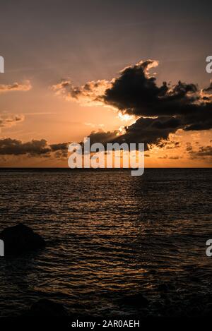 Sonnenuntergang über dem Meer mit großen Wolken vor der Sonne Stockfoto