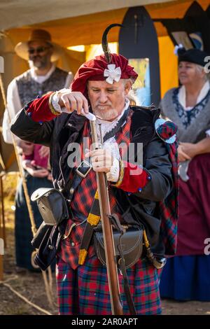 Mitglied der Scottish Living History Gruppe im traditionellen Kleid demonstriert das Laden des Flintlock-Gewehrs auf dem Glen Innes Celtic Festival NSW Stockfoto