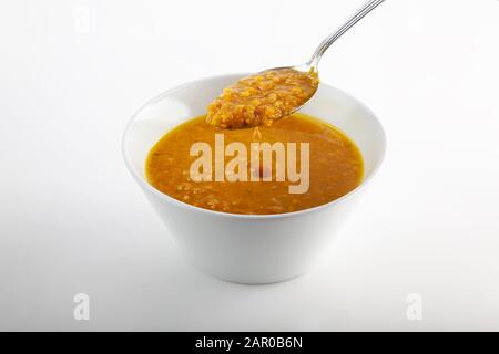 Studio mit einem Kürbisminestrone in einer Tasse ohne Griffe und einem Löffel, der auf weißem Hintergrund zu essen bereit ist Stockfoto