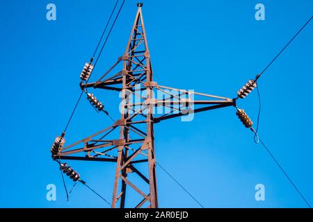 Alter rostiger Hochspannungspol vor blauem Himmel Hintergrund Stockfoto