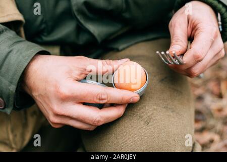 Der als Soldat Der US-Infanterie Des zweiten Weltkriegs Gekleidete Re-Enactor Hält Während des Frühstücks Eierhalter In Händen. Nahaufnahme. Stockfoto