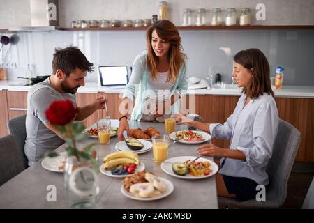 Lächelnde Freunde frühstücken in der Küche und haben Spaß Stockfoto