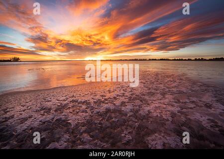 Der in Loveland Colorado Gelegene LON Hagler Reservoir friert während der Wintermonate über, während die Sonne an einem Januar-Morgen über den Horizont auftaucht Stockfoto