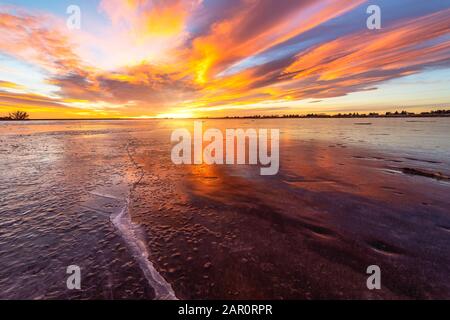 Der in Loveland Colorado Gelegene LON Hagler Reservoir friert während der Wintermonate über, während die Sonne an einem Januar-Morgen über den Horizont auftaucht Stockfoto