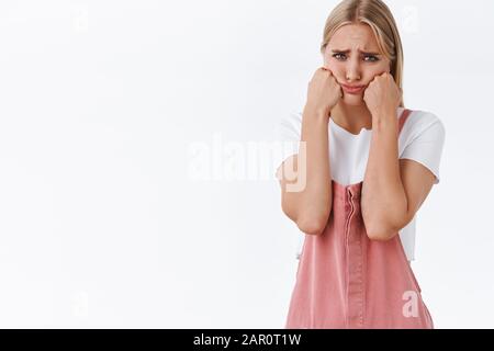 Verärgerte kindliche und albern süße blonde Freundin, die sich schlecht und beleidigt fühlt, weinte, drückte Wangen aus, die unleicht und einsam aussehen, peitschen, sulking Stockfoto