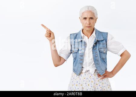 Wütende, ernsthaft aussehende enttäuschte Seniorin, Großmutter unzufrieden mit schlechtem Verhalten, frohlockend, links mit Verachtung und Bestürzung, fordernd Stockfoto