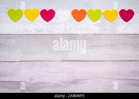 Bunte Filz Herzen auf dem Hintergrund der alten hölzernen Planken ähnelt einem alten Parkettboden. Konzept der Valentinstag und die Liebe im Allgemeinen. Stockfoto