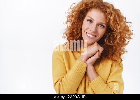 Taillenhoch Portrait, schöne, lockige Rotkopffrau in gelbem Pullover, Anzug für christmass Party in warmem, gemütlichem Outfit, Klammerhände zusammen und lächelnd Stockfoto