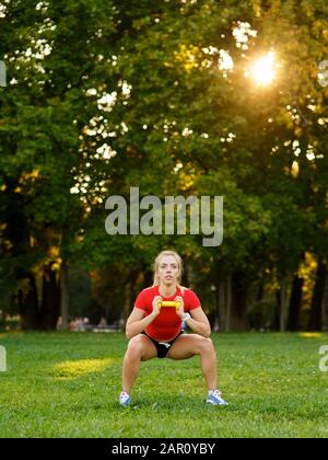 Ein junges Mädchen kann Sport treiben, mit Hanteln in der Natur, Fitnessfrau im Freien im Park trainieren Stockfoto