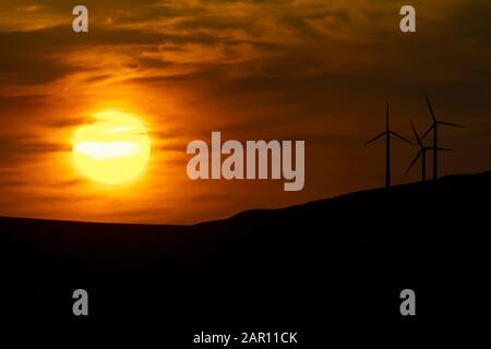 Sonnenuntergang über den Bergen mit Windkraftanlagen in der Grafschaft donegal irland Öko Energie und erneuerbare Energien Konzept Stockfoto