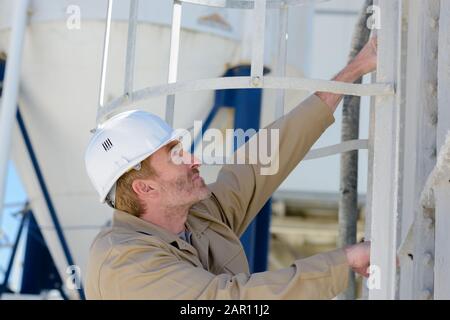 Raffineriearbeiter klettern auf das Silo Stockfoto