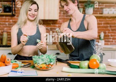Ernährung, gesunde Ernährung, Fitness-Lifestyle, richtige Ernährung. Gesundheitsbewusste Paare kochen kalorienarm Abendessen in der Hausküche. Ein Mann gießt Olivenöl Stockfoto