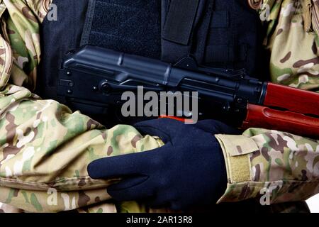 Mann im Kampf Ermüdungserscheinungen und schusssichere Jacke, die die Aks-47u im Nahkampf Kampfflugschussgewehr bewaffnete Wache ausländische Militärmilizen umhüllt Stockfoto