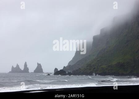 Nebel rollt über dem schwarzen Sandstrand reynisfjall Berg Und reynisdrangar Basaltgestein von vik i myrdal im Süden island Stockfoto