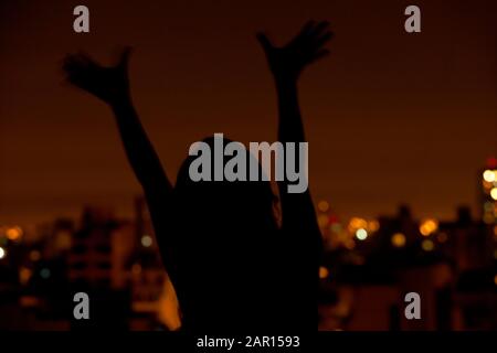 Junge alleinstehende Frau, die vor Freude an der Silhouette gegen die Skyline der Stadt sprang buenos aires argentinien Modell veröffentlichte Bild Stockfoto