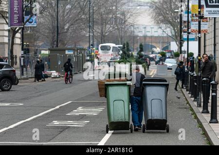 London, Großbritannien - 1. Januar 2020: Nach der Silvesterfeier reinigt der Mann die Straße und nimmt die Abfallbehälter heraus Stockfoto