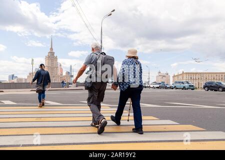 Russland Moskau 2019-06-17 Altes Paar hält Hände und geht auf Fußgängerüberweg. Konzept aktives Alter, Hobbys, Reisen, Touristen im Alter, aktives e Stockfoto