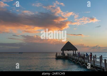 Karibischer Sonnenuntergang im Januar. Die Sonne malte die Wolken sanft orange. Stockfoto