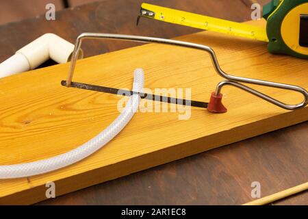 Mit einer Junior-Hack-Säge wird ein kleines Stück Kunststoffschlauch geschnitten Stockfoto