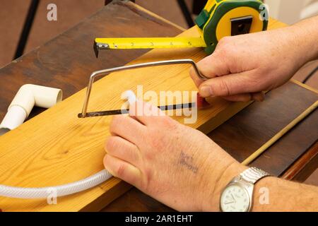 Mit einer Junior-Hack-Säge wird ein kleines Stück Kunststoffschlauch geschnitten Stockfoto