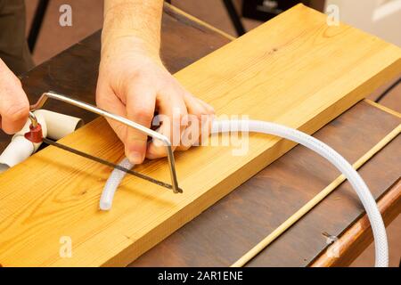 Mit einer Junior-Hack-Säge wird ein kleines Stück Kunststoffschlauch geschnitten Stockfoto