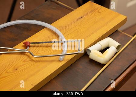 Mit einer Junior-Hack-Säge wird ein kleines Stück Kunststoffschlauch geschnitten Stockfoto