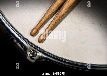 Nahaufnahme von zwei Holztrommeln auf einer alten metallischen Snare-Trommel mit dunklem Hintergrund. Schlaginstrument Stockfoto