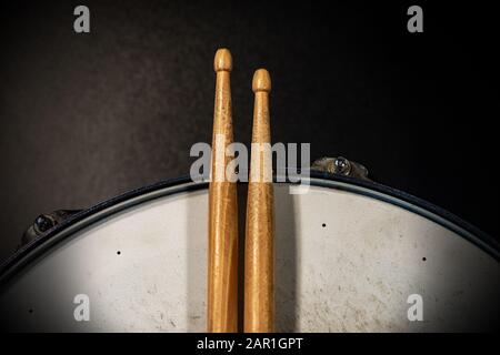 Nahaufnahme von zwei Holztrommeln auf einer alten metallischen Snare-Trommel mit dunklem Hintergrund. Schlaginstrument Stockfoto