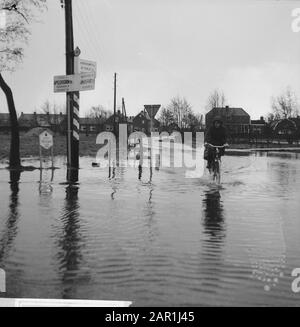 Waternuisance in Kootwijcurbroek (in der Nähe von Barneveld), jemand, der durch das Wasser radeln Datum: 10. Dezember 1965 Ort: Gelderland, Kootwijcurbroek Schlagwörter: Radfahrer, Überschwemmungen, Waternuisance Stockfoto