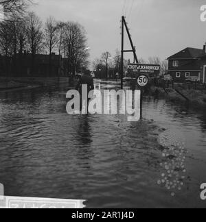 Waternuisance in Kootwijcurbroek (in der Nähe von Barneveld), jemand, der durch das Wasser läuft Datum: 10. Dezember 1965 Ort: Gelderland, Kootwijcurbroek Schlüsselwörter: Namensschilder, Überschwemmungen, Verkehrszeichen, Wassereinschlag Stockfoto