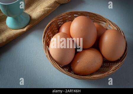 Eier im Korb mit Eierbecher auf grauem Tisch, ostern. Stockfoto