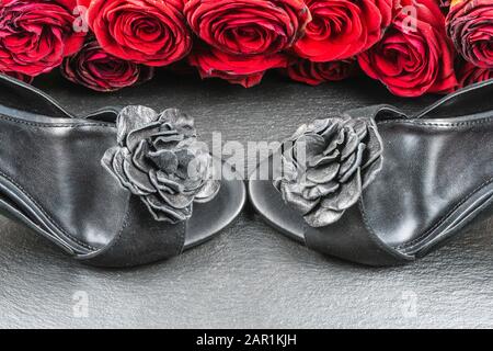 Schuhe mit hohem Absatz, Rosen auf schwarzem Steingrund Stockfoto