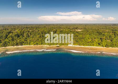 Dichter Regenwald säumt einen langen Sandstrand an der Küste von Bougainville, Papua-Neuguinea, das vorgelagerte Riff schimmert in mehreren Blautönen. Stockfoto