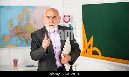 Sie sollten studieren. Bärtiger Mann gibt Spuren. Schreiben Sie Notizen in Buch. Strenger leitender Dozent macht Notizen. Lehrer für Geographie. Klassenzimmer mit Karte und Tafel. Zurück zur Schule. Mathematikausbildung in der Schule. Stockfoto