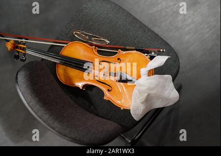 Musikinstrumente: Geige und Bogen auf dem Musikerstuhl Stockfoto