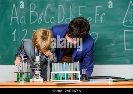 Wir schätzen die Innovation, Sohn und Vater in der Schule. Weisheit. Zurück zur Schule. Chemie und Physikbiologie. Mit Reagenzgläsern in wissenschaftlicher Hand fragen. Kleiner Junge mit Lehrmann. Stockfoto