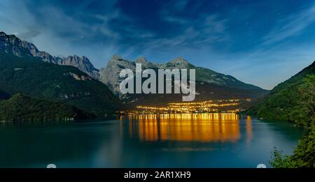 Der schöne Molveno in der Nacht mit der Lichtreflexion auf dem großen See. Im Hintergrund sind große Berge Stockfoto