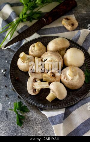 Champignons. Frische weiße Pilze in Schüssel auf Steingrund. Stockfoto