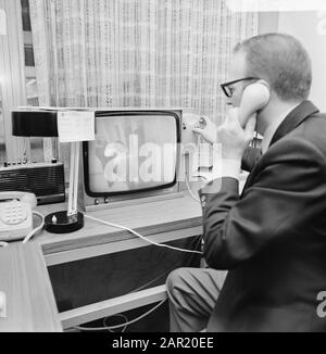 Geschlossener TV-Schaltkreis zur Sicherheit in den Presse- und Konferenzräumen Schiphol Mitarbeiter am Telefon hinter dem Bildschirm Datum: 3. Januar 1974 Standort: Noord-Holland, Schiphol Schlüsselwörter: Sicherheit, Fernsehbildschirme Stockfoto