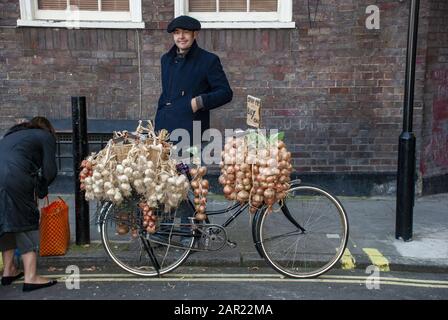 London, GROSSBRITANNIEN - 3. November 2007: Französischer Zwiebelverkäufer mit seinem Fahrrad mit Knoblauch und Zwiebeln Stockfoto