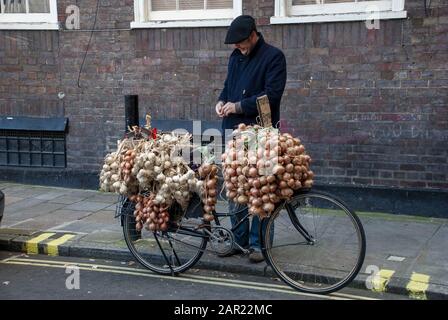 London, GROSSBRITANNIEN - 3. November 2007: Französischer Zwiebelverkäufer mit seinem Fahrrad mit Knoblauch und Zwiebeln Stockfoto