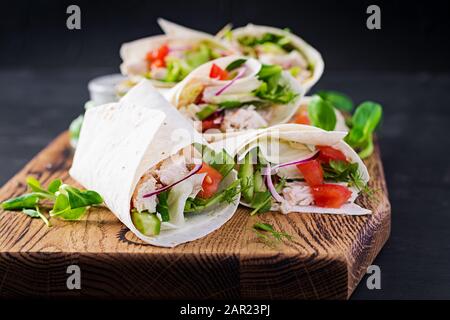 Frische Tortilla-Wraps mit Huhn und frischem Gemüse auf Holzbrett. Hühnerburrito. Mexikanische Küche. Gesundes Lebensmittelkonzept. Mexikanische Küche. Stockfoto